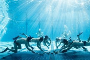 Подводный хоккей в бассейне: игроки в масках и ластах на дне